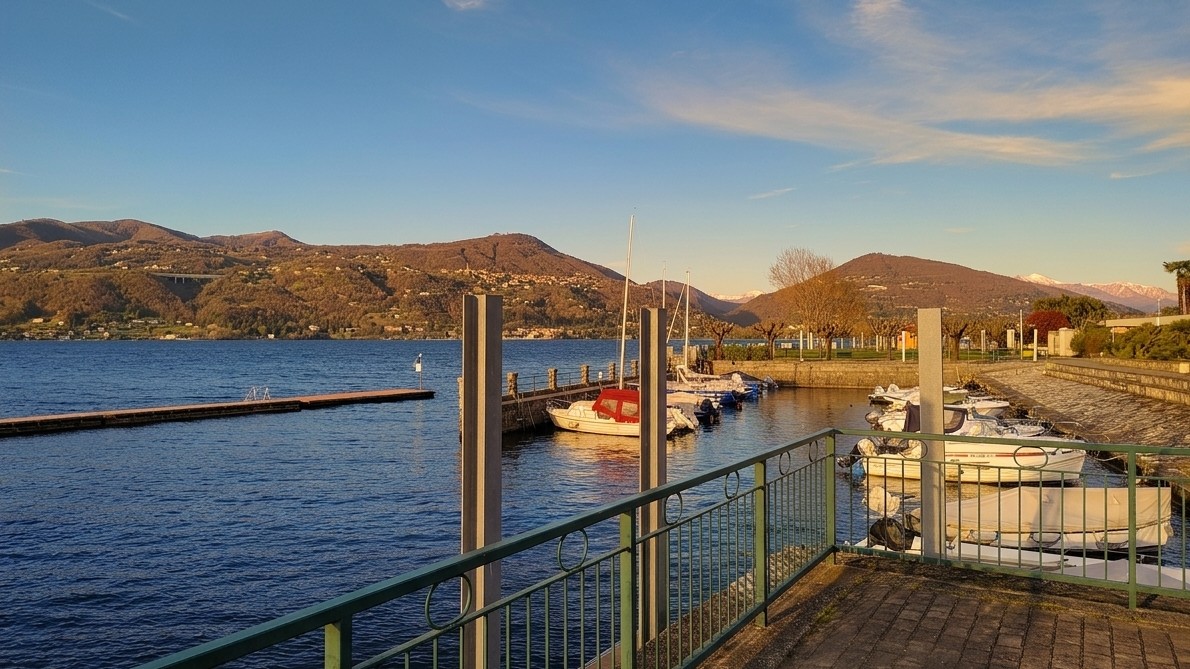 Vista sul Lago Maggiore da Ranco, con i monti e le barche ormeggiate al tramonto